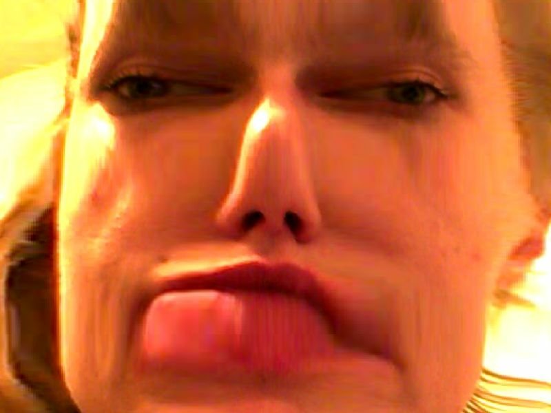 Close-up selfie of a woman's face distorted by a filter, features compressed and puckered lips creating a stretched, exaggerated expression.