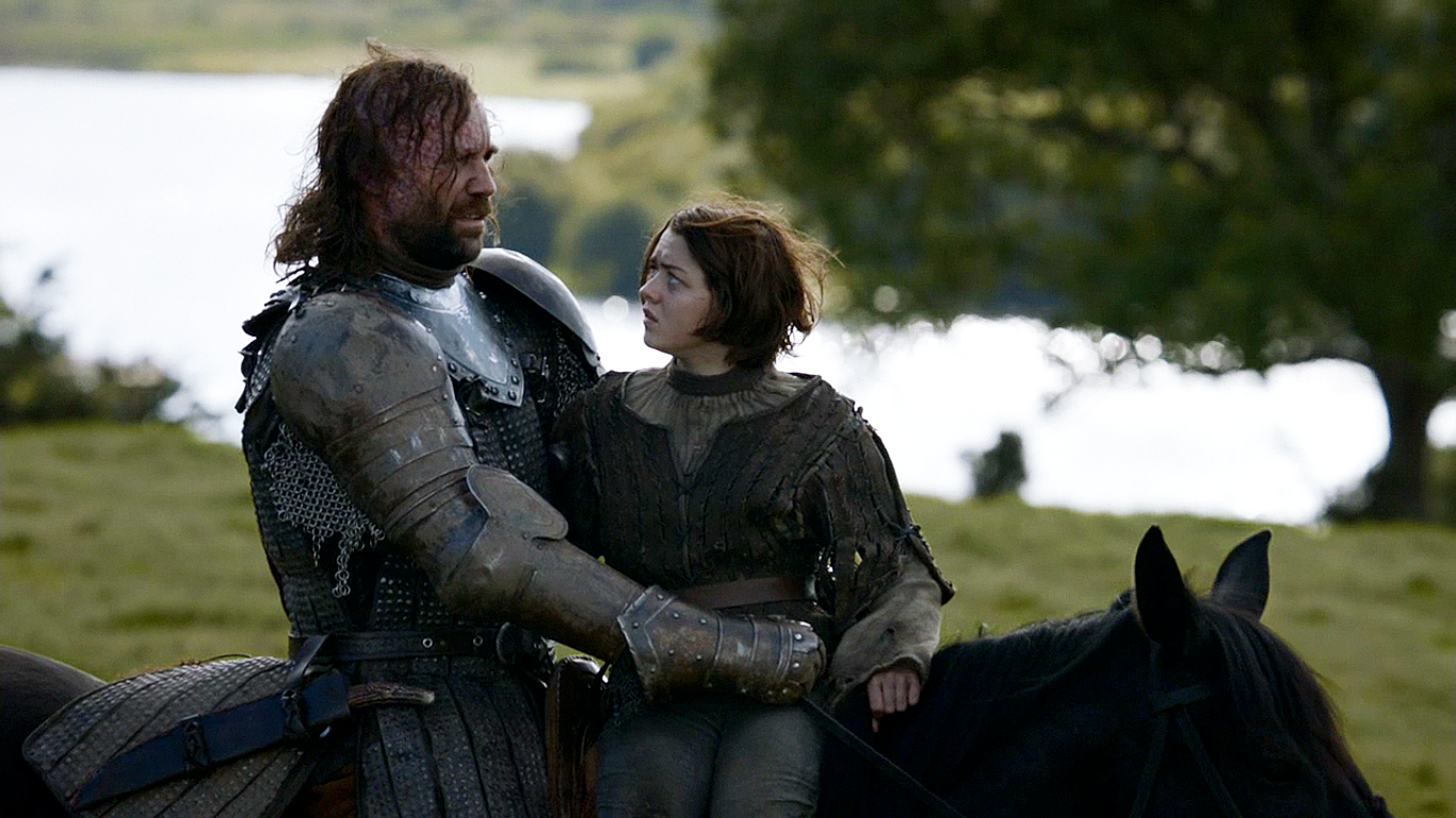 Maisie Williams as Arya Stark and Rory McCann as Sandor Clegane share a moment on horseback in a scenic landscape from the TV show Game of Thrones.