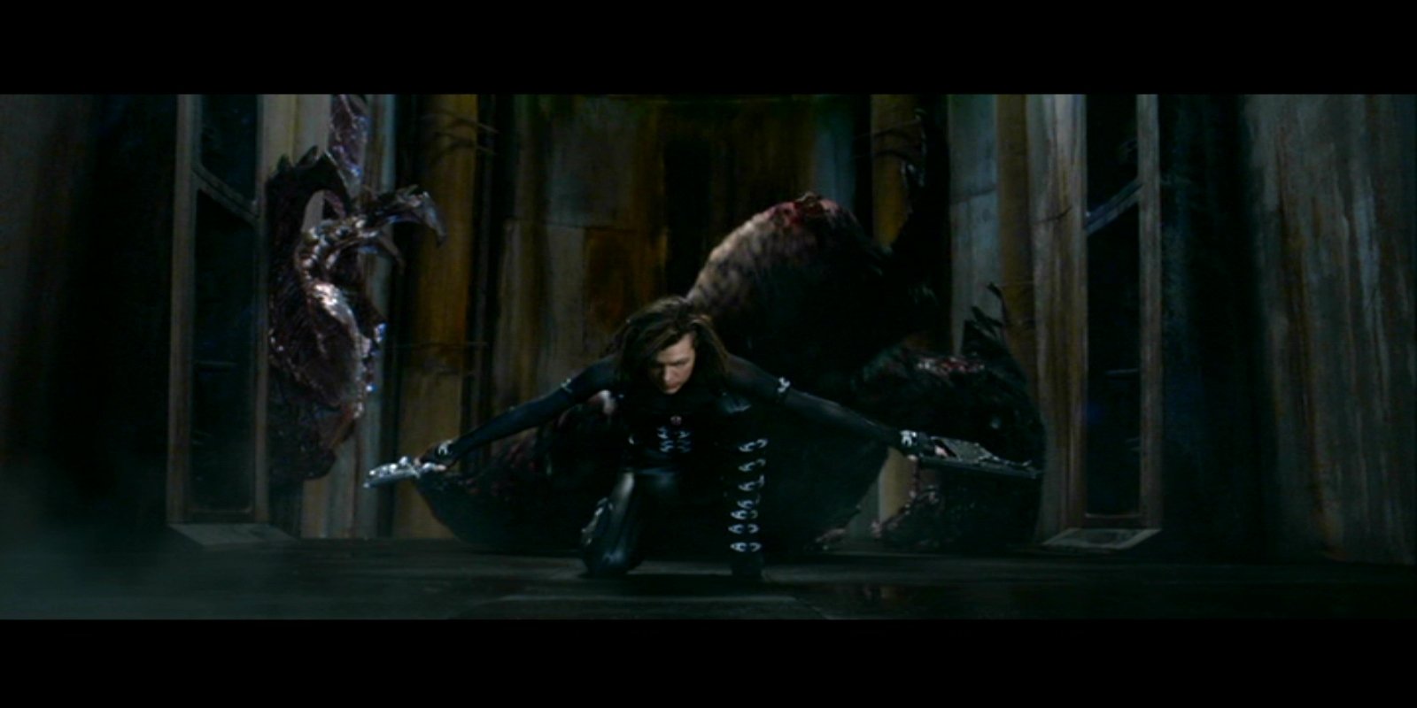 A scene from the movie Resident Evil: Retribution shows a character crouching defensively in front of a menacing, monstrous creature inside a dark, dilapidated building.