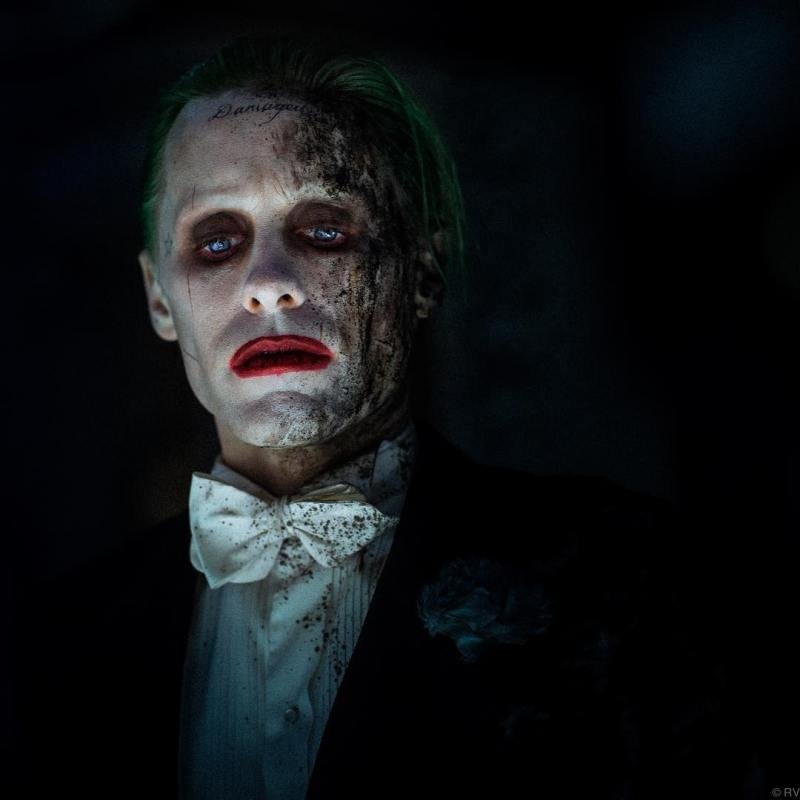 Jared Leto as the Joker in *Suicide Squad*, features a haunting portrayal with distinct green hair, smeared makeup, and a tattered suit, capturing the character's chaotic essence.