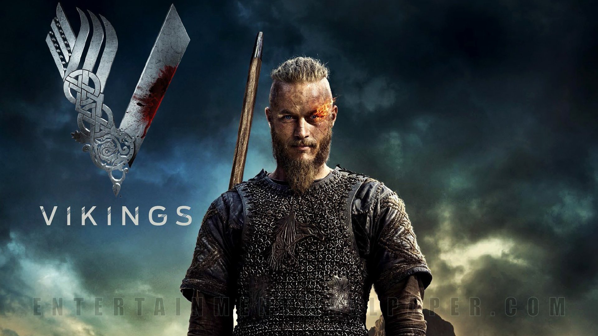 Ragnar Lothbrok stands fiercely in armor with a sword, representing the iconic character from the TV show Vikings (2013), set against a dramatic cloudy backdrop.