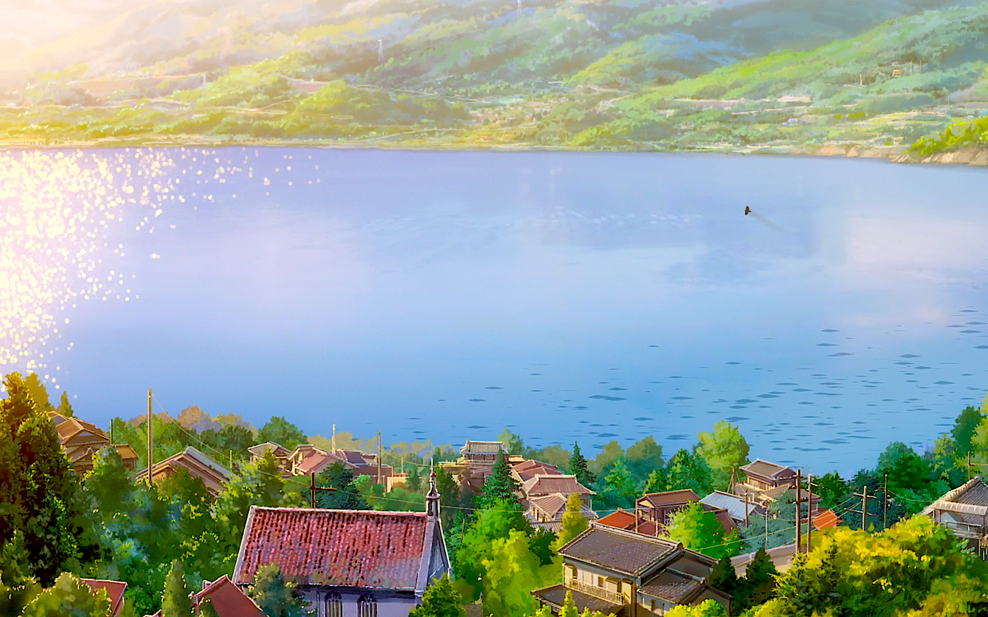 A serene view of Itomori town by a sparkling lake from the anime Your Name., with sunlight illuminating the lush green hills and rooftops.