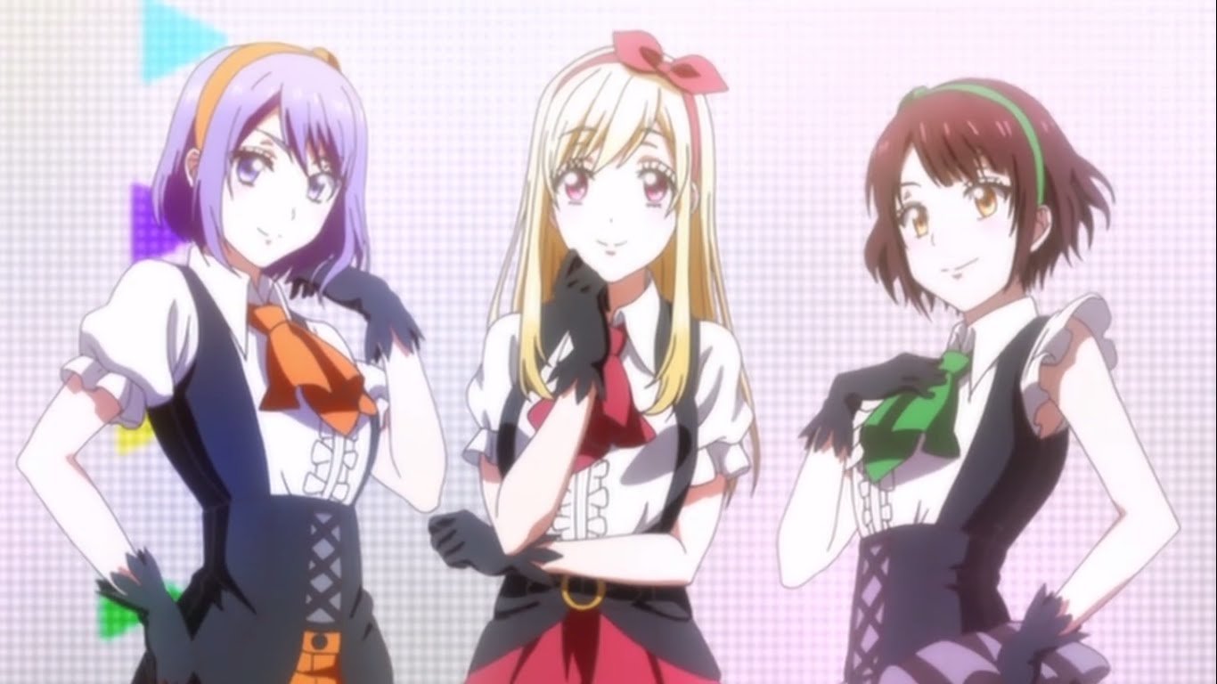Three girls in coordinated stage outfits from the anime Yamada-kun and the Seven Witches, posing confidently against a soft pastel background.
