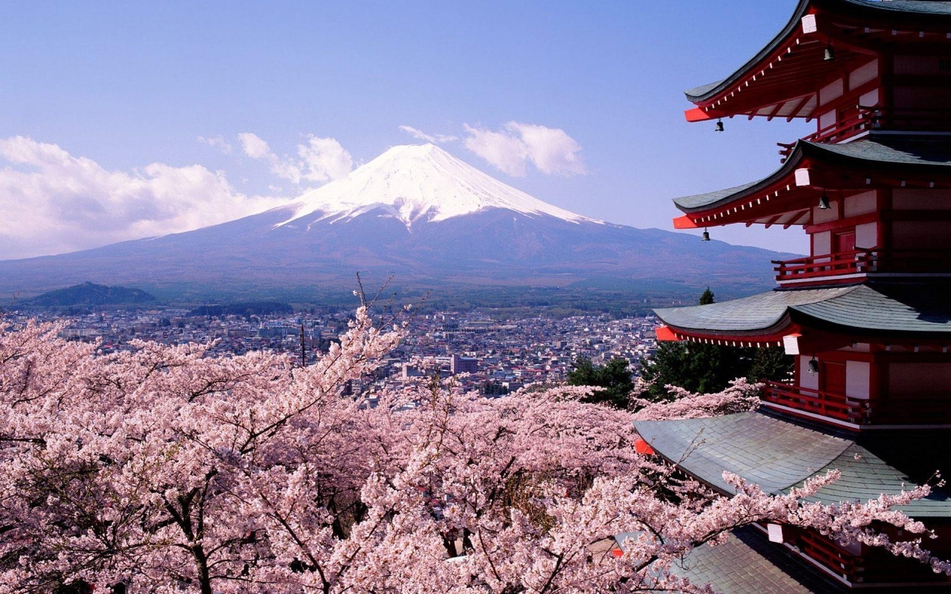 A stunning view of Mount Fuji, towering majestically in the background, framed by cherry blossoms and a traditional Japanese pagoda, showcasing the beauty of Japan's nature.