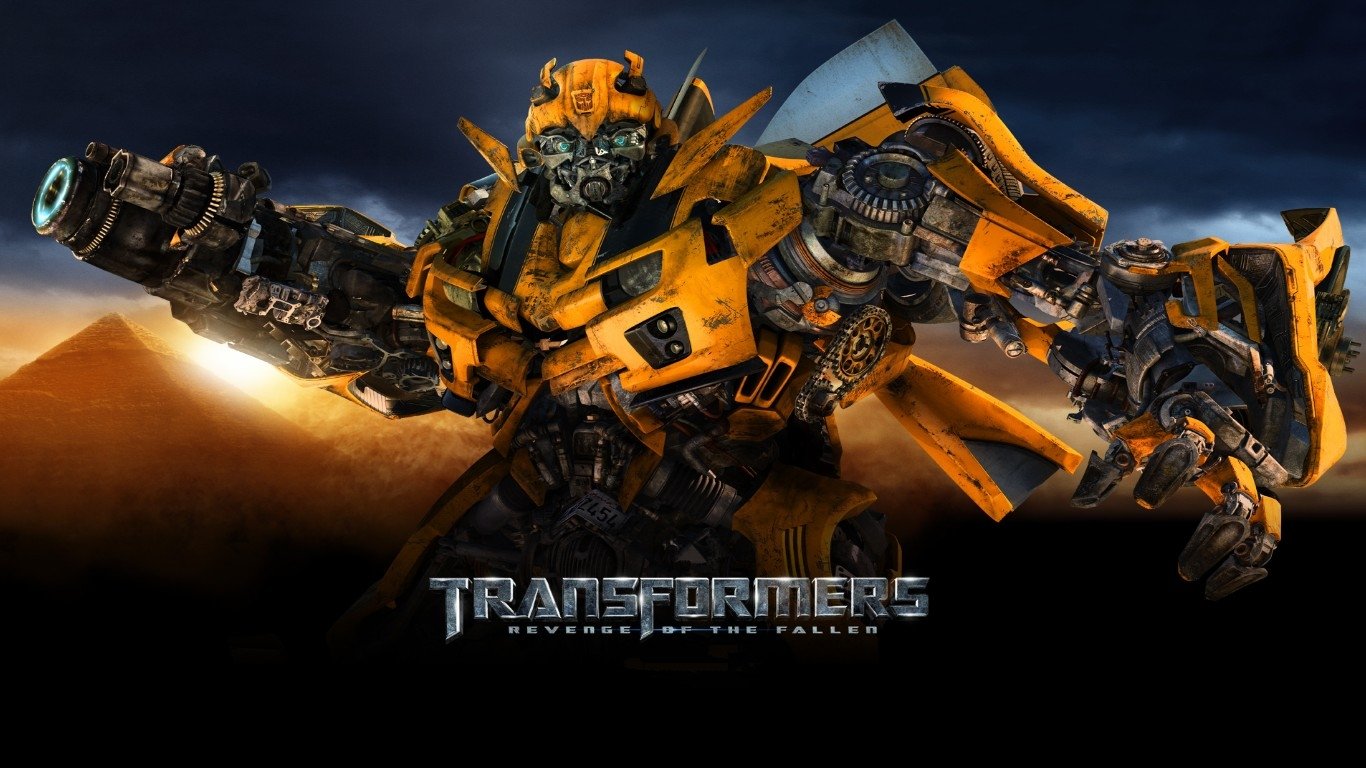 Yellow Autobot Bumblebee from the movie Transformers: Revenge of the Fallen raises a weapon against a stormy sky, film logo visible at the bottom.