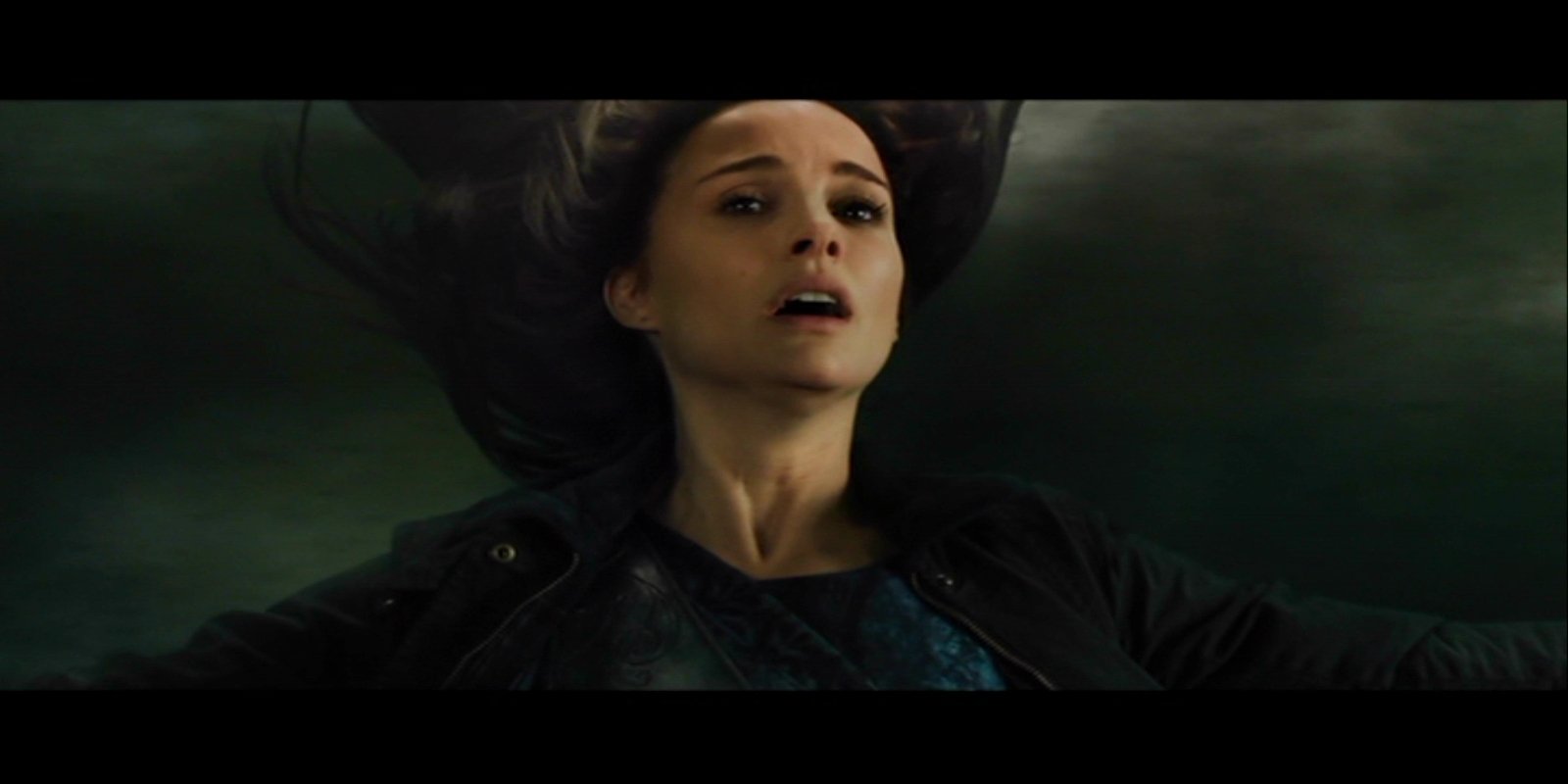 A tense scene from the movie Thor: The Dark World shows a woman with flowing hair against a dark, stormy sky.
