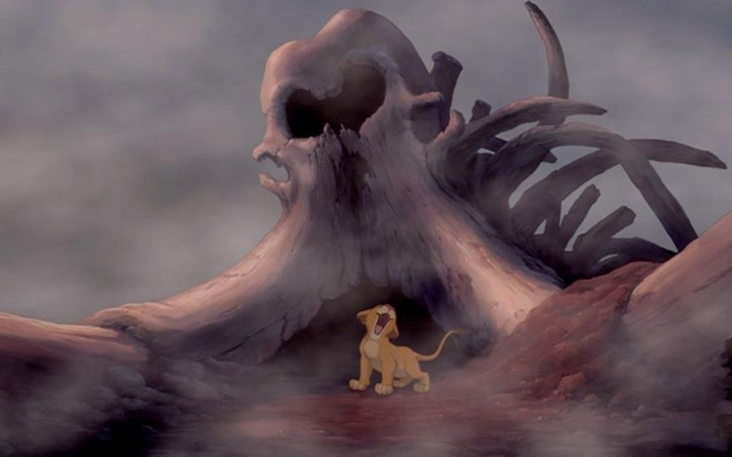 A scene from The Lion King (1994) showing young Simba standing before a large, skull-shaped rock formation in a misty, eerie landscape.