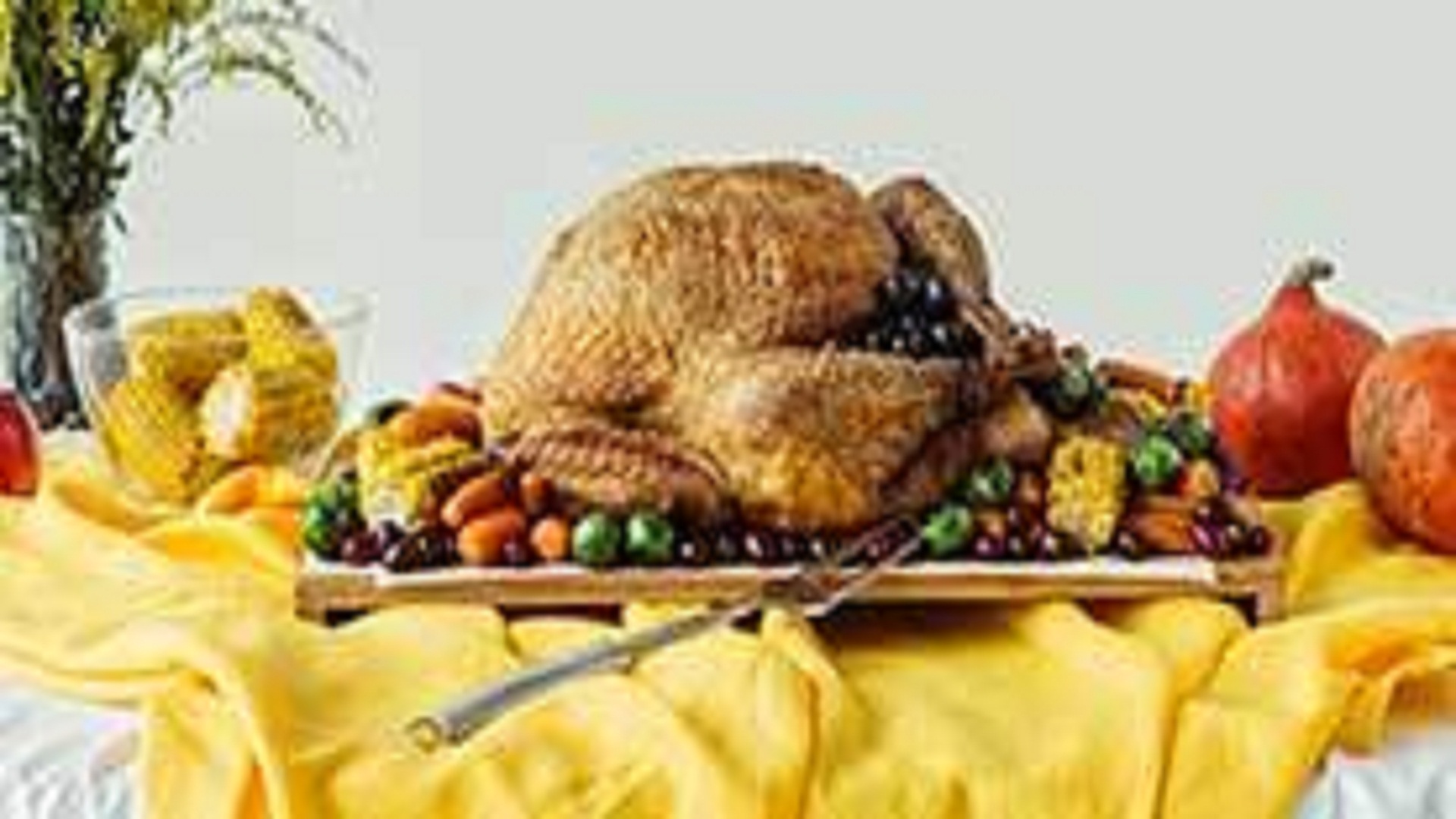 Close up view of holiday dinner table set with roasted turkey and vegetables on grey background,