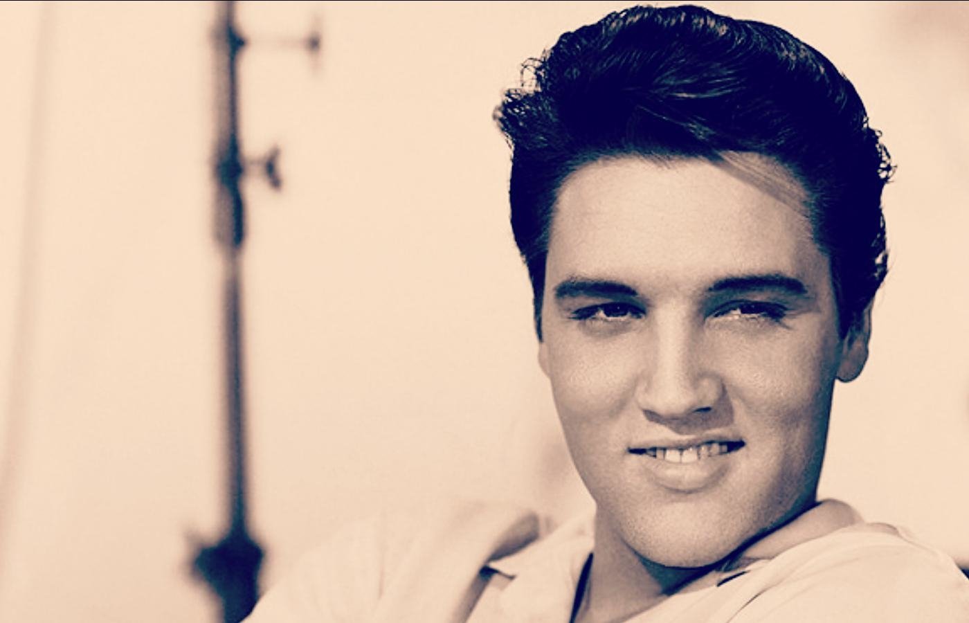 Black and white portrait of Elvis Presley, the iconic Rock & Roll musician, smiling with a confident expression.