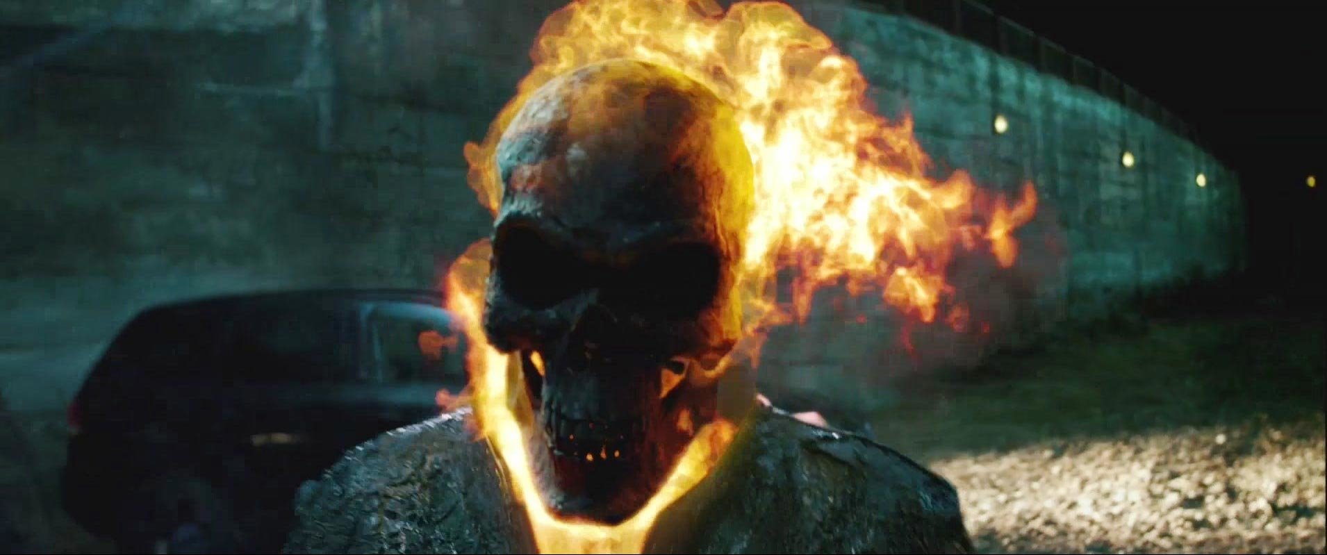 Ghost Rider from the movie Ghost Rider: Spirit of Vengeance — a flaming skull and blazing head set against a dark urban wall.