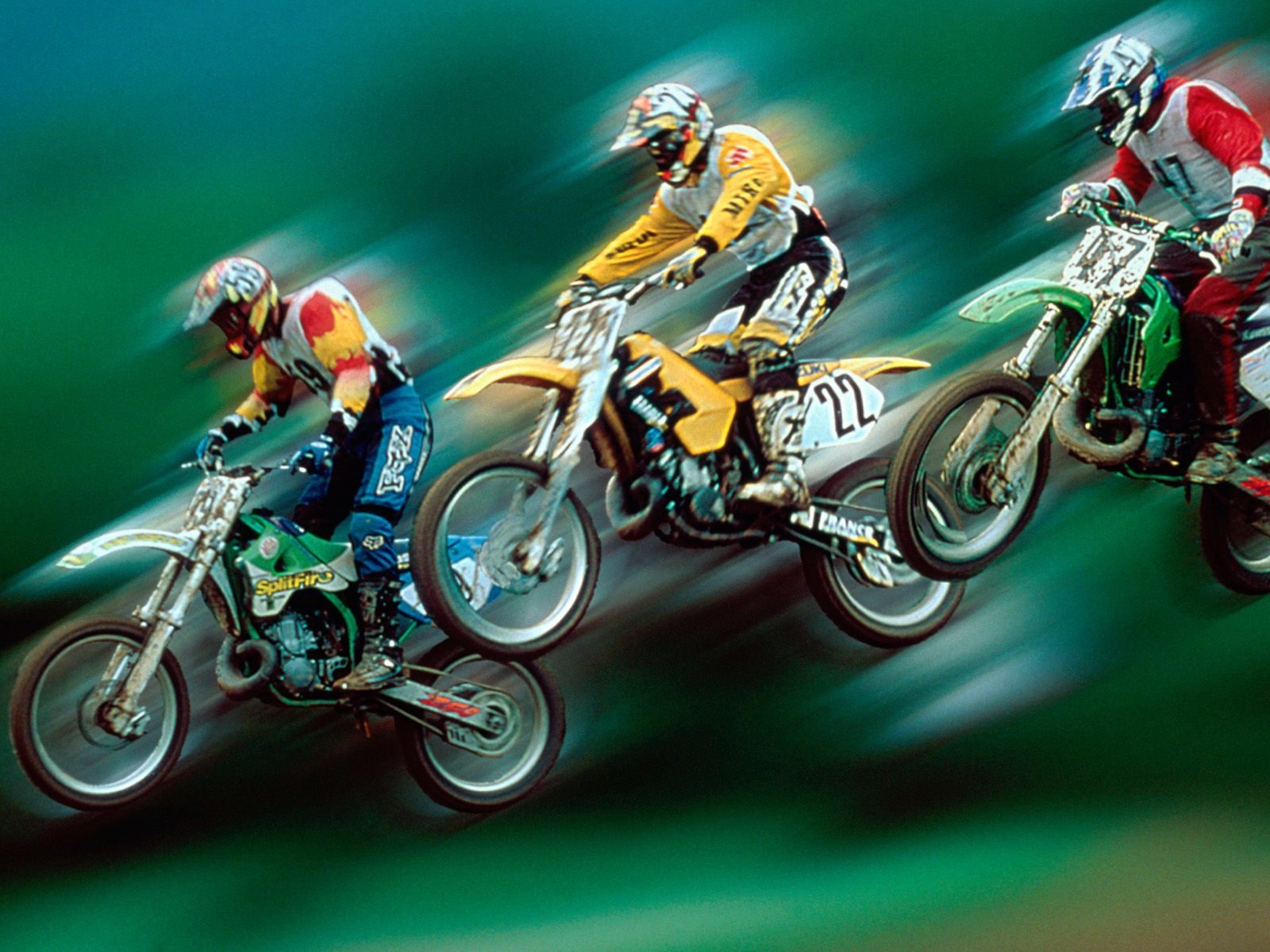Three motocross riders in action, soaring through the air on their bikes, showcasing the thrill and excitement of the sport against a dynamic, blurred background.