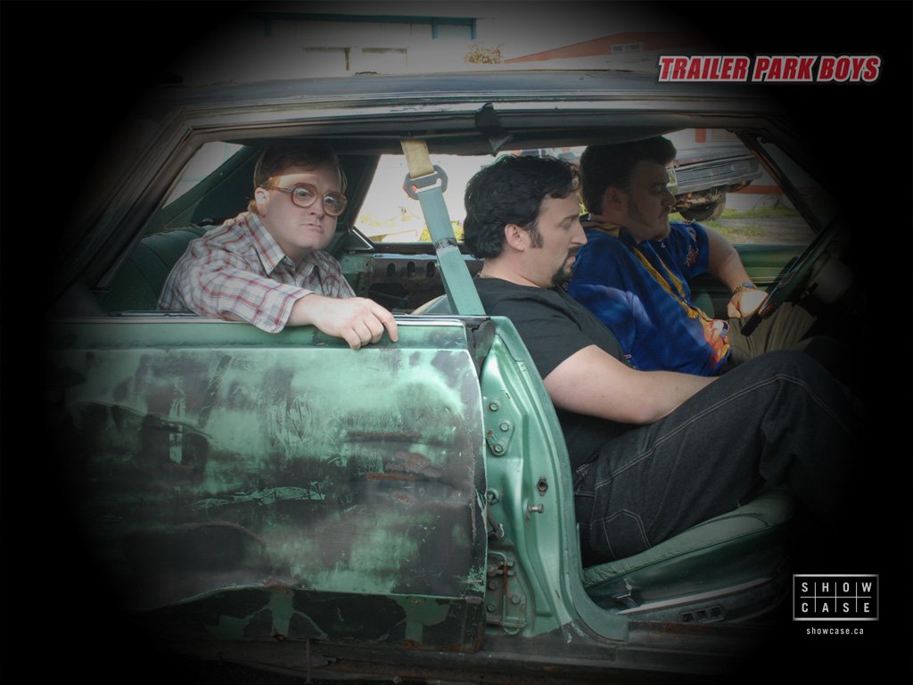 Three characters from the TV show Trailer Park Boys sit in a dilapidated car, with one wearing glasses, showcasing the show's comedic vibe and unique charm.