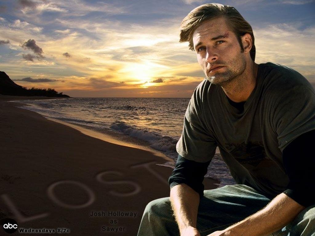 A man sits on the beach at sunset, gazing thoughtfully toward the ocean, with the word LOST written in the sand, reminiscent of the TV show.