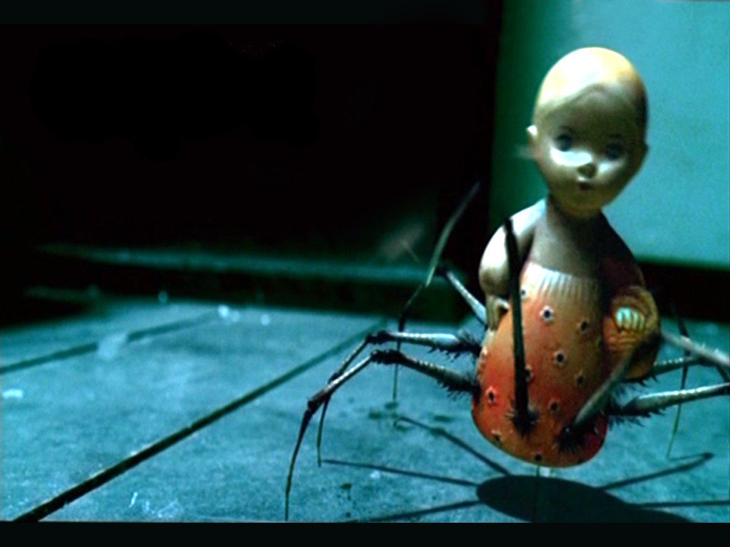 A dark and scary image featuring a doll with a human face and spider-like legs, creating an unsettling and eerie atmosphere. The setting enhances its sinister nature.