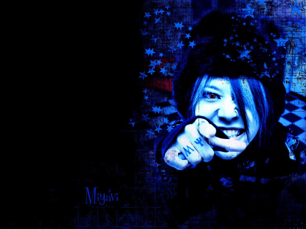 Portrait of J-Rock artist Miyavi with a vibrant blue filter, striking a dynamic pose with a fist toward the camera, embodying his energetic music style.