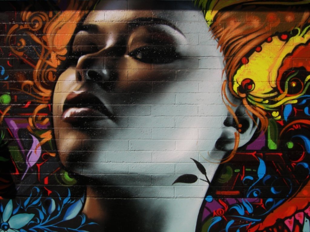 A striking piece of artistic graffiti featuring a close-up of a woman's face, adorned with vibrant colors and intricate floral patterns, blending realism with bold creativity.