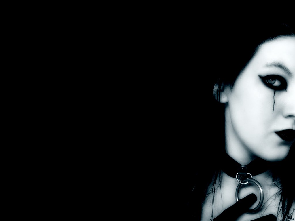 A striking emo figure is partially illuminated against a dark backdrop, showcasing gothic elements with dramatic makeup, black attire, and a choker that enhances the mysterious aesthetic.