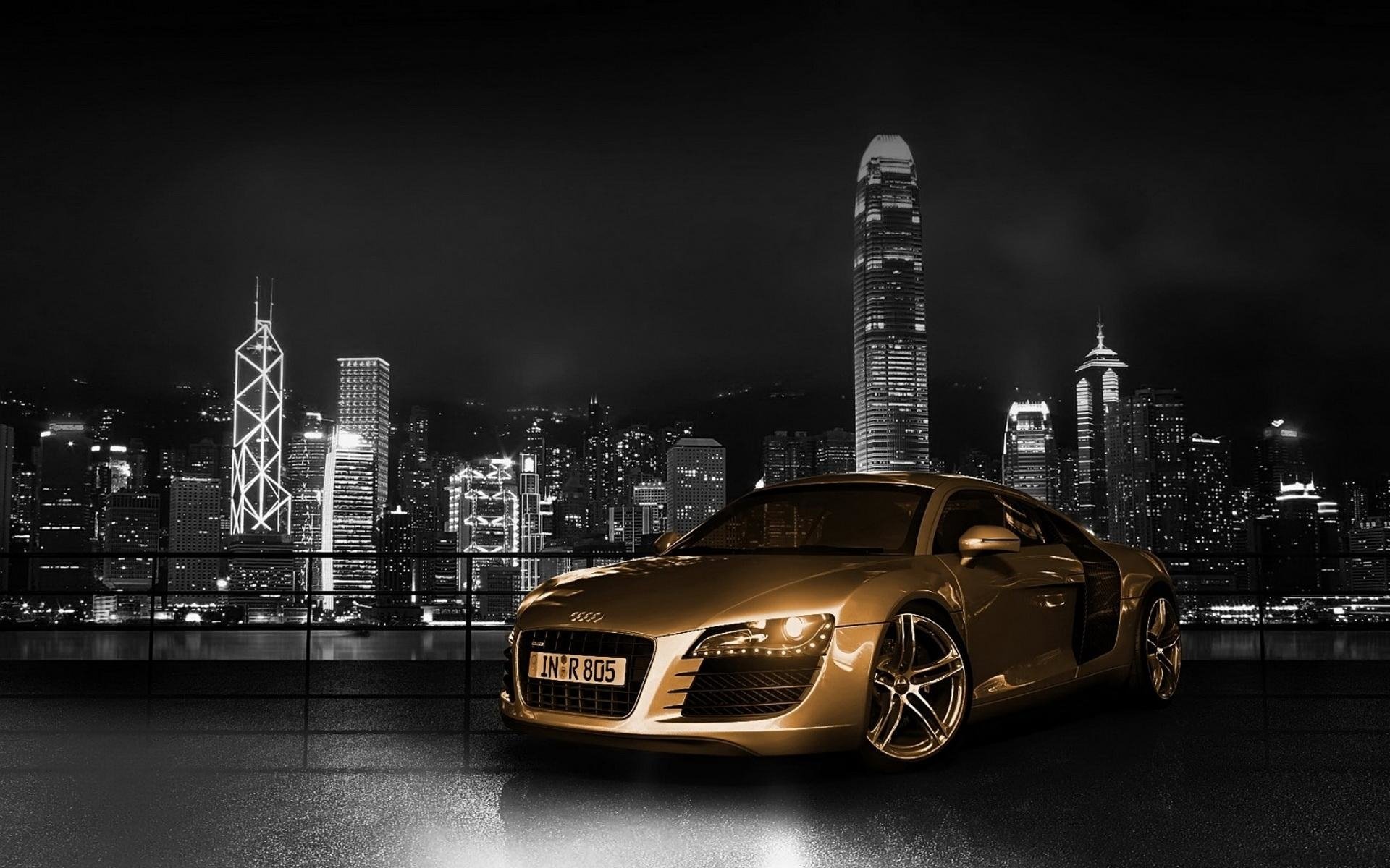 An Audi R8 is showcased in a vibrant cityscape at night, illuminated by skyscraper lights, reflecting luxury and performance against a moody backdrop.