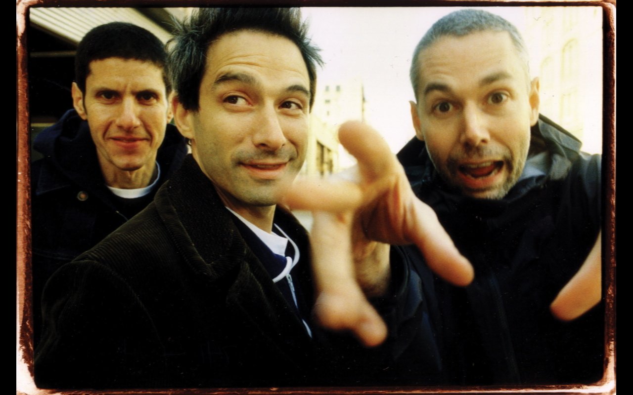 The Beastie Boys pose energetically, showcasing their playful and dynamic spirit in this candid music-themed photo.