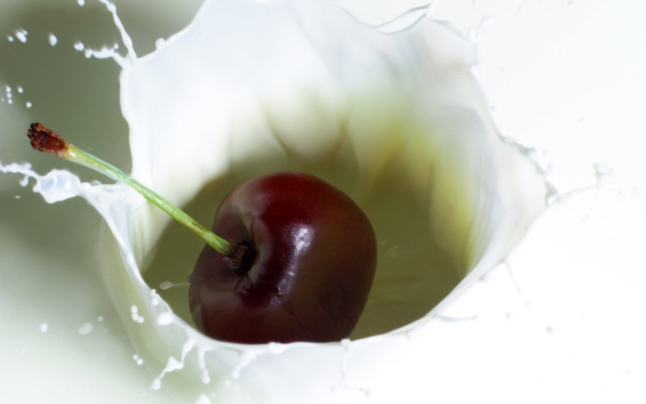 A vibrant cherry splashes into a pool of milk, creating an artistic burst of water droplets around it, celebrating the beauty of food in motion.