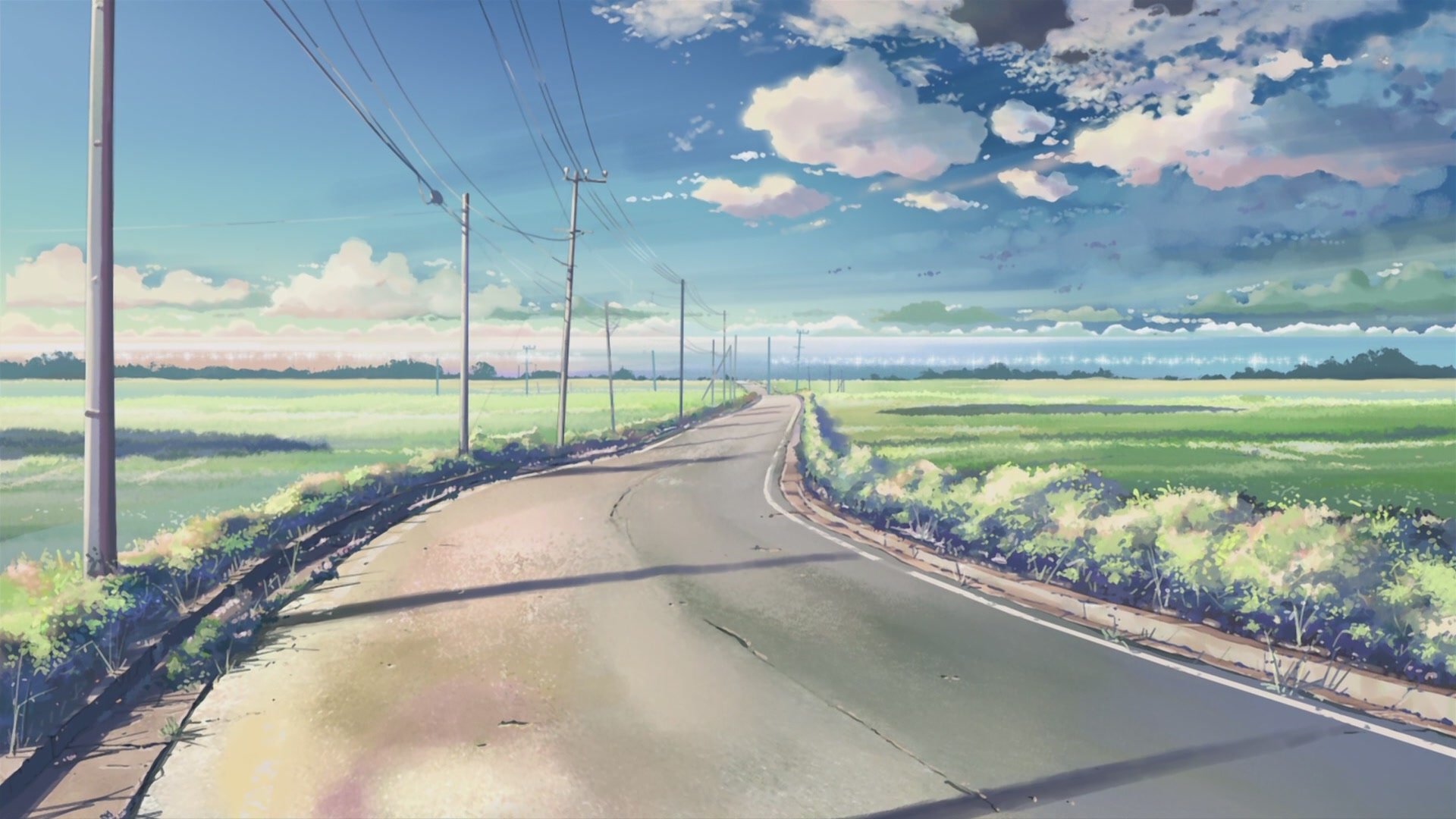 A serene landscape from the anime 5 Centimeters per Second, featuring a winding road bordered by lush fields and a vibrant sky filled with fluffy clouds.