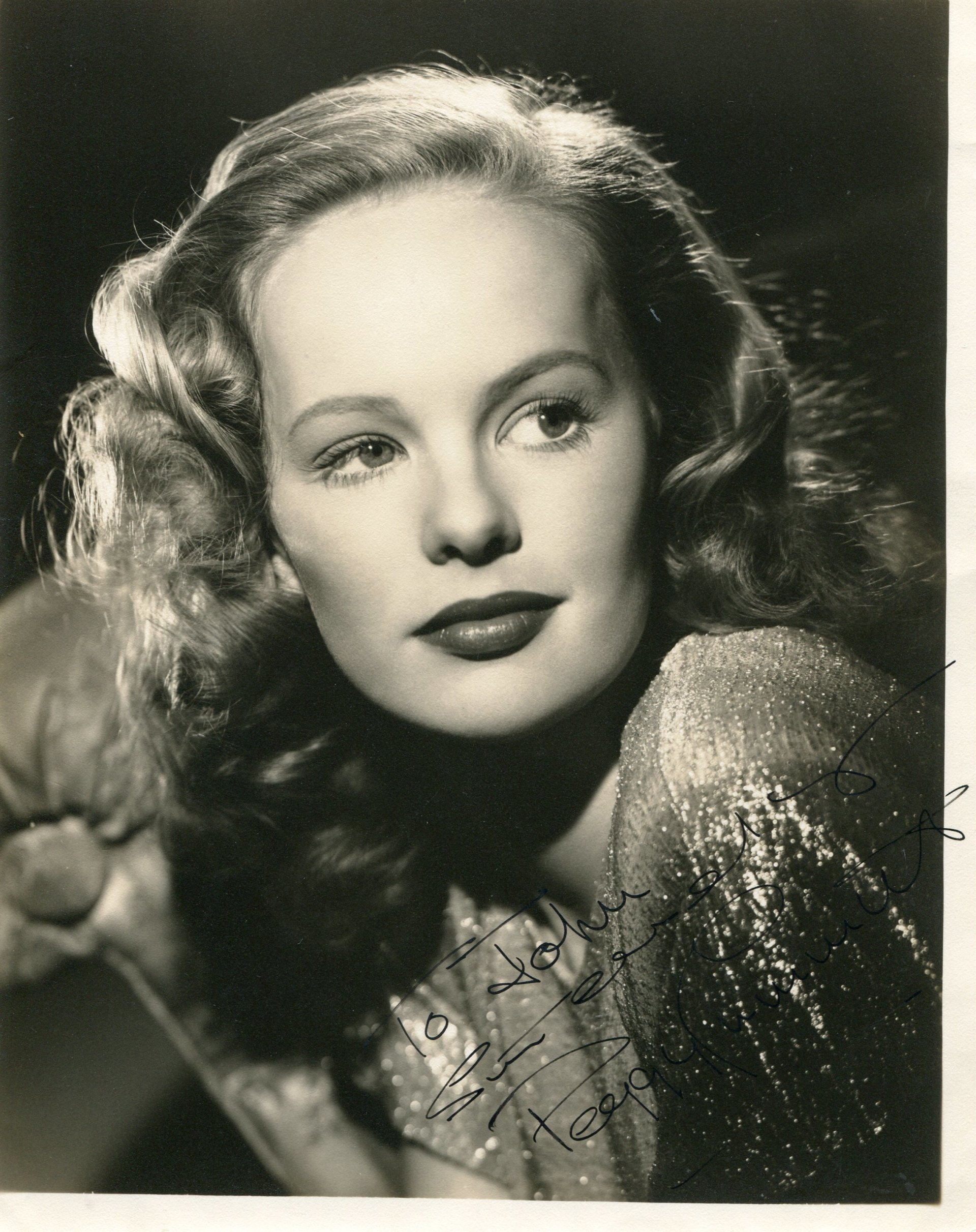 A black-and-white portrait of celebrity Peggy Cummins, featuring her signature, showcasing her glamorous hairstyle and striking features.