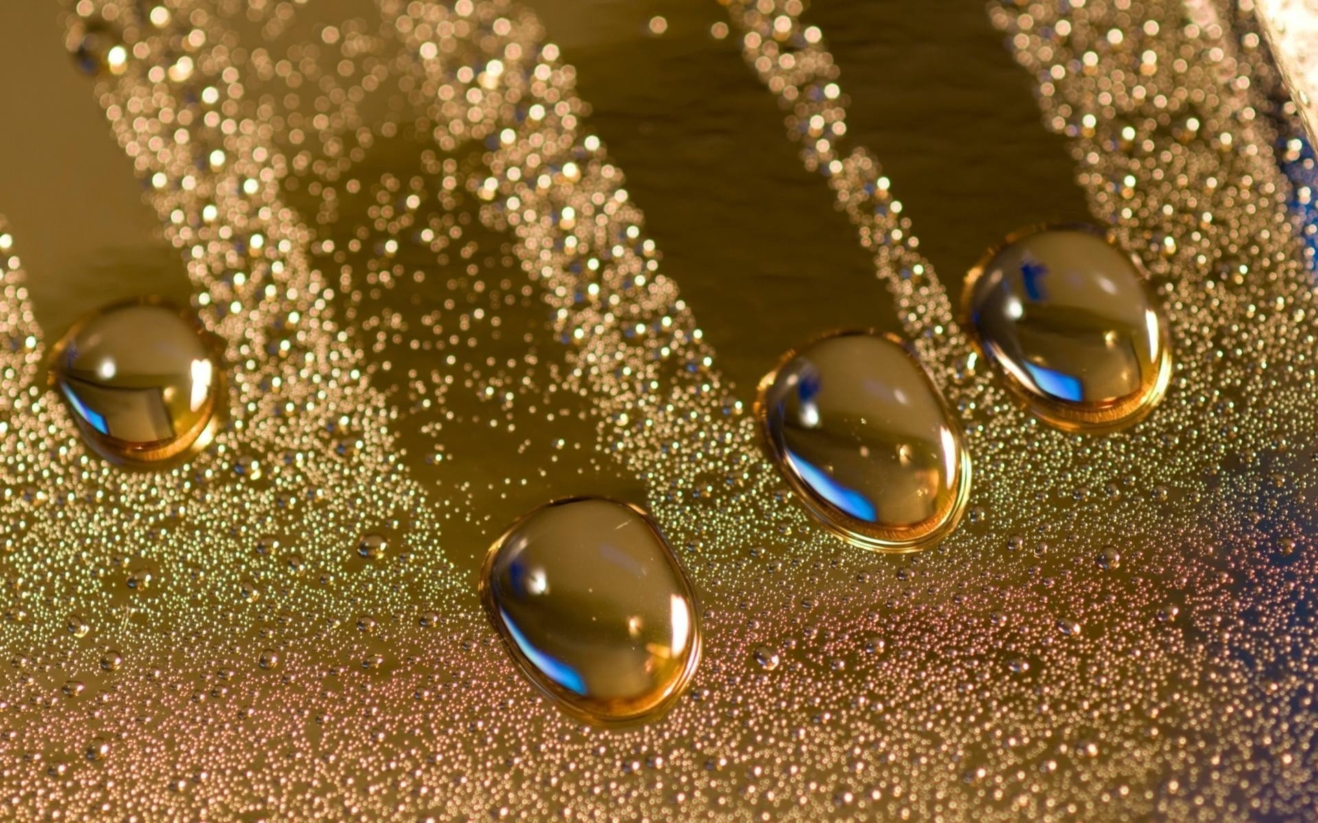 A close-up photography of water drops on a textured surface, showcasing their glistening details and surrounding tiny bubbles. The colors create an appealing, reflective effect.