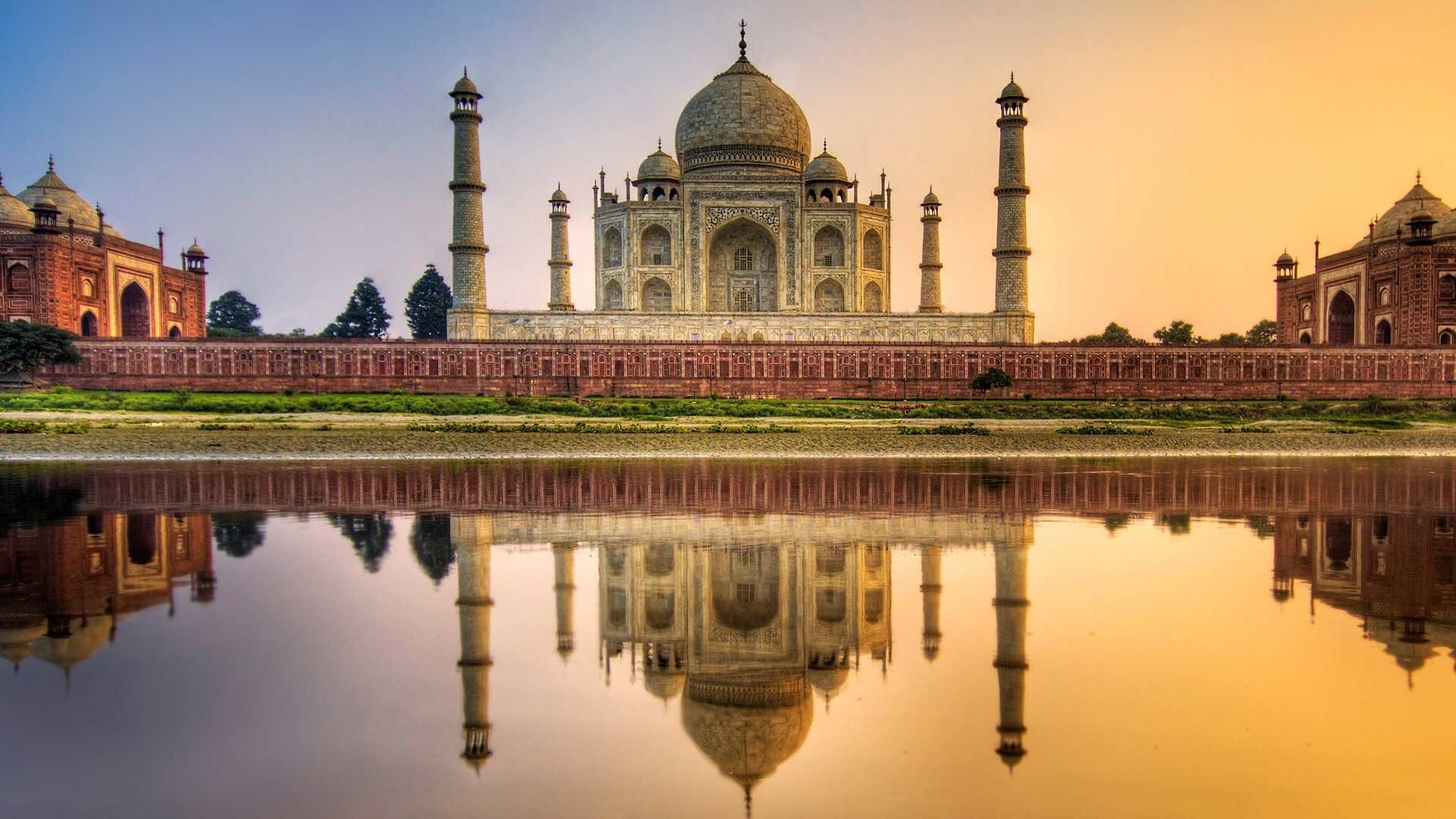 A breathtaking view of the Taj Mahal, a stunning man-made architectural marvel, reflected in the calm waters at sunrise, showcasing its intricate design and serene beauty.