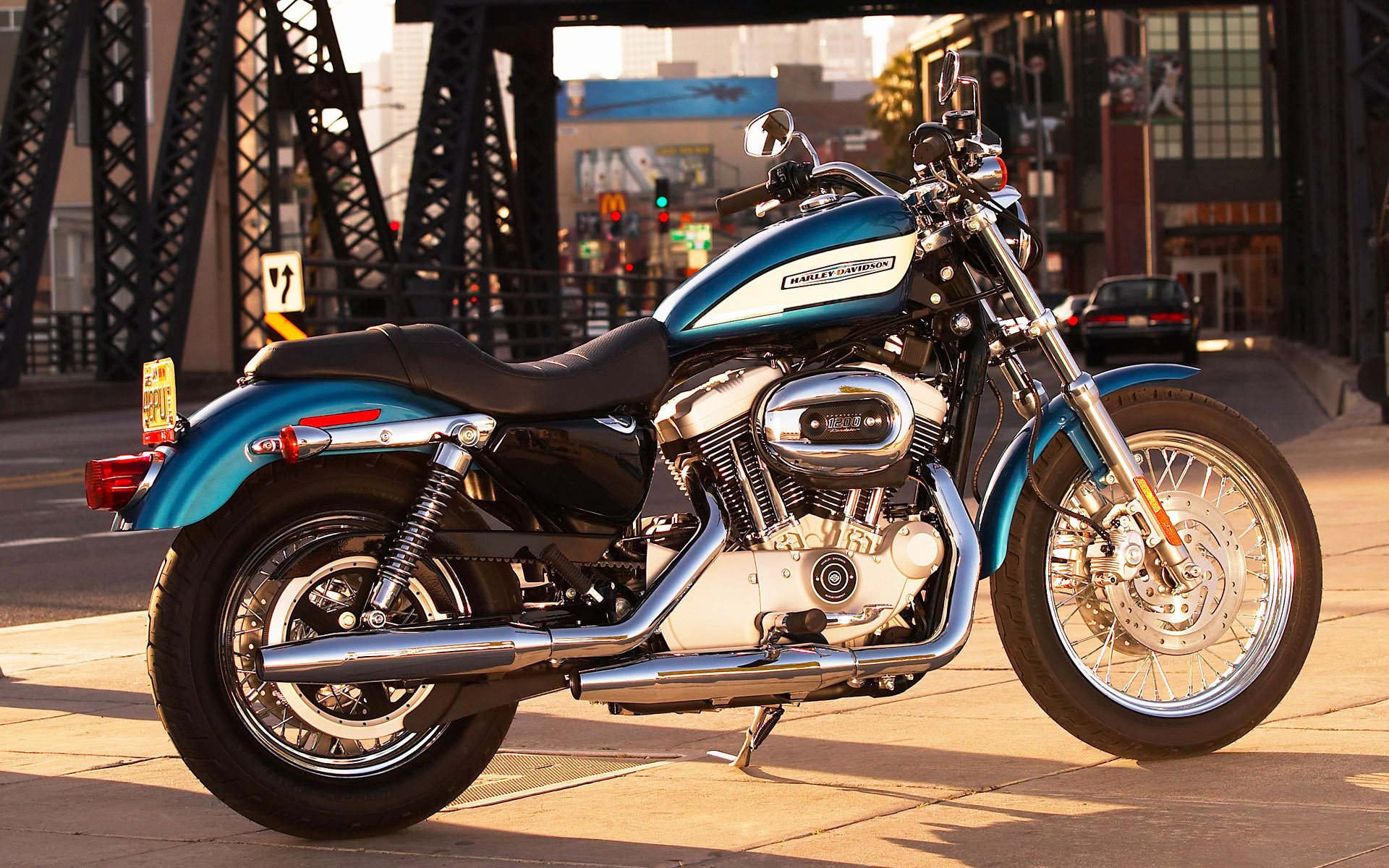 A vibrant blue Harley-Davidson motorcycle parked on a city street, showcasing its sleek design and chrome details against an urban backdrop.