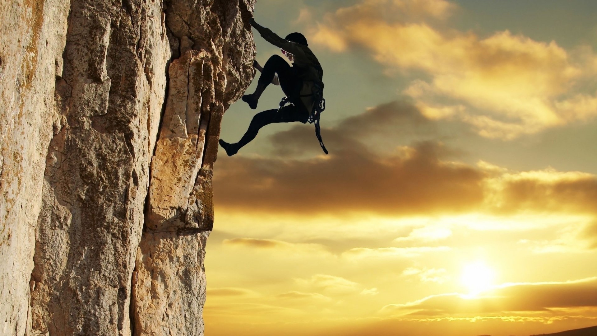 A climber ascends a rocky cliff against a stunning sunset, showcasing the thrill and challenge of climbing sports.