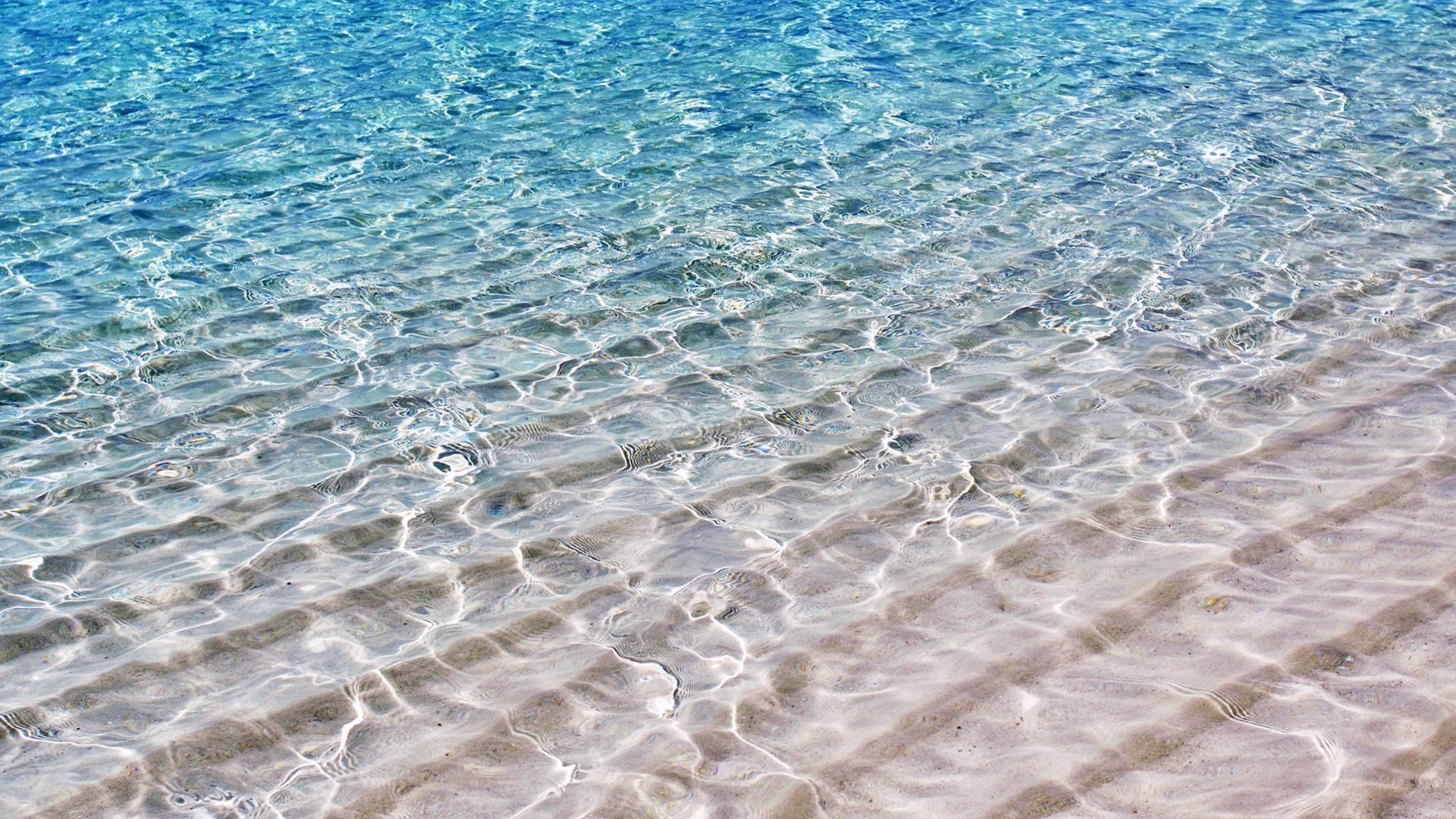 Clear, shallow water rippling over a sandy bottom, showcasing the natural beauty of water in a serene outdoor setting.