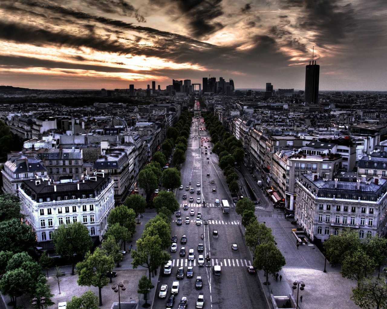 A sweeping aerial view of Paris at sunset, showcasing bustling streets lined with trees and elegant buildings under a dramatic sky. The city’s vibrant energy is palpable.
