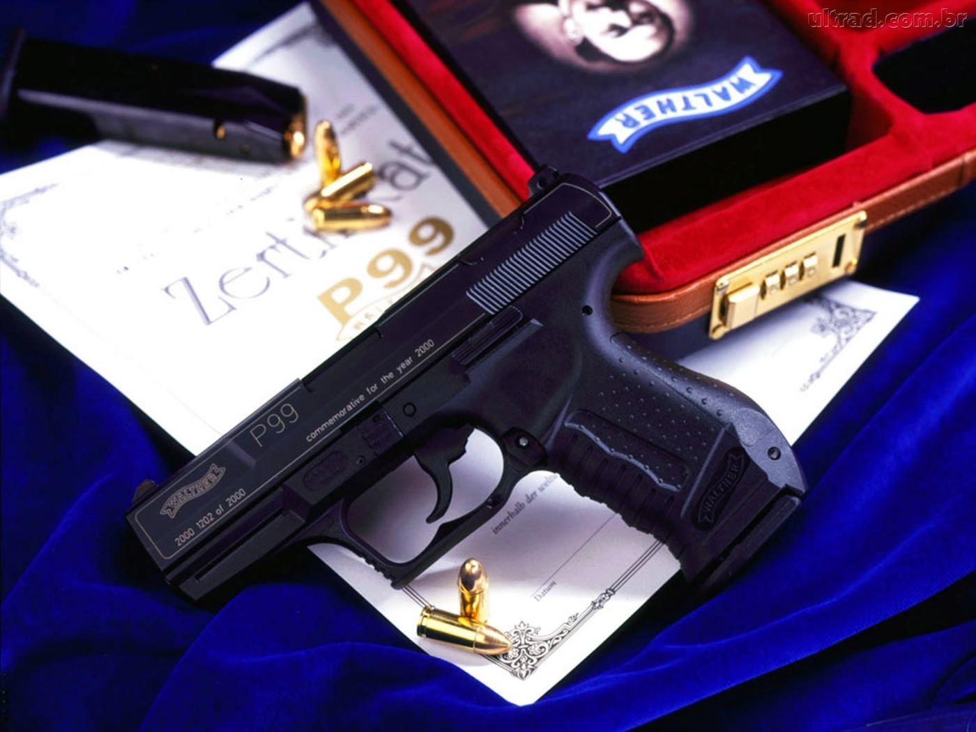 A black handgun sits on a blue velvet surface, accompanied by spent cartridge casings and a certificate labeled Zertifikat P-99, all inside an open velvet-lined case.