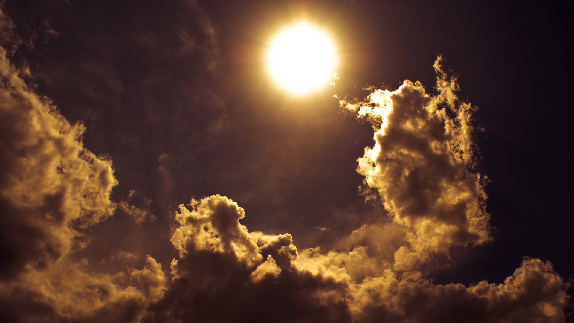 Bright sun shining through dark, dramatic clouds in a striking nature scene.