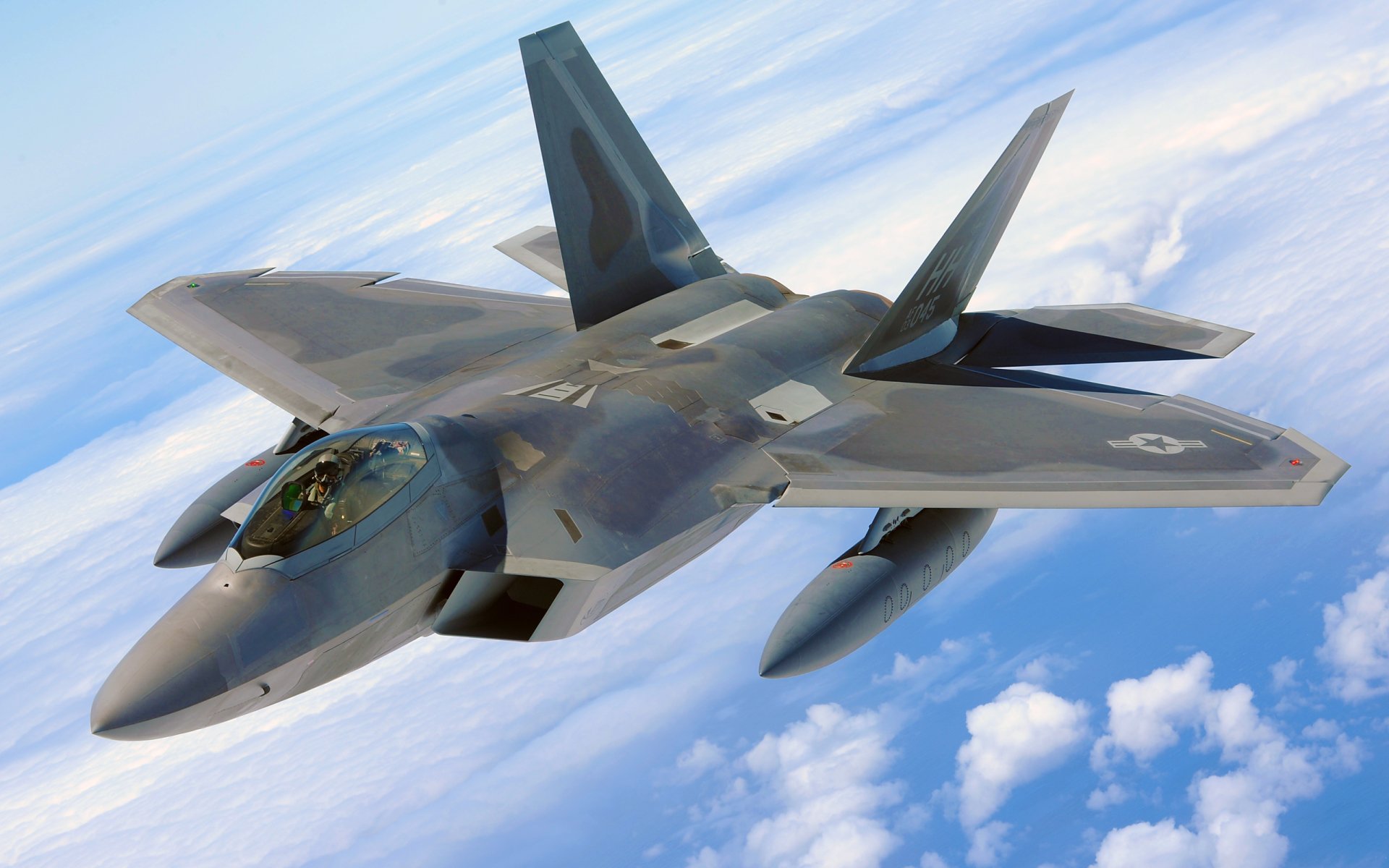 A Lockheed Martin F-22 Raptor flies high above the clouds, showcasing its sleek design and advanced capabilities in military aviation.