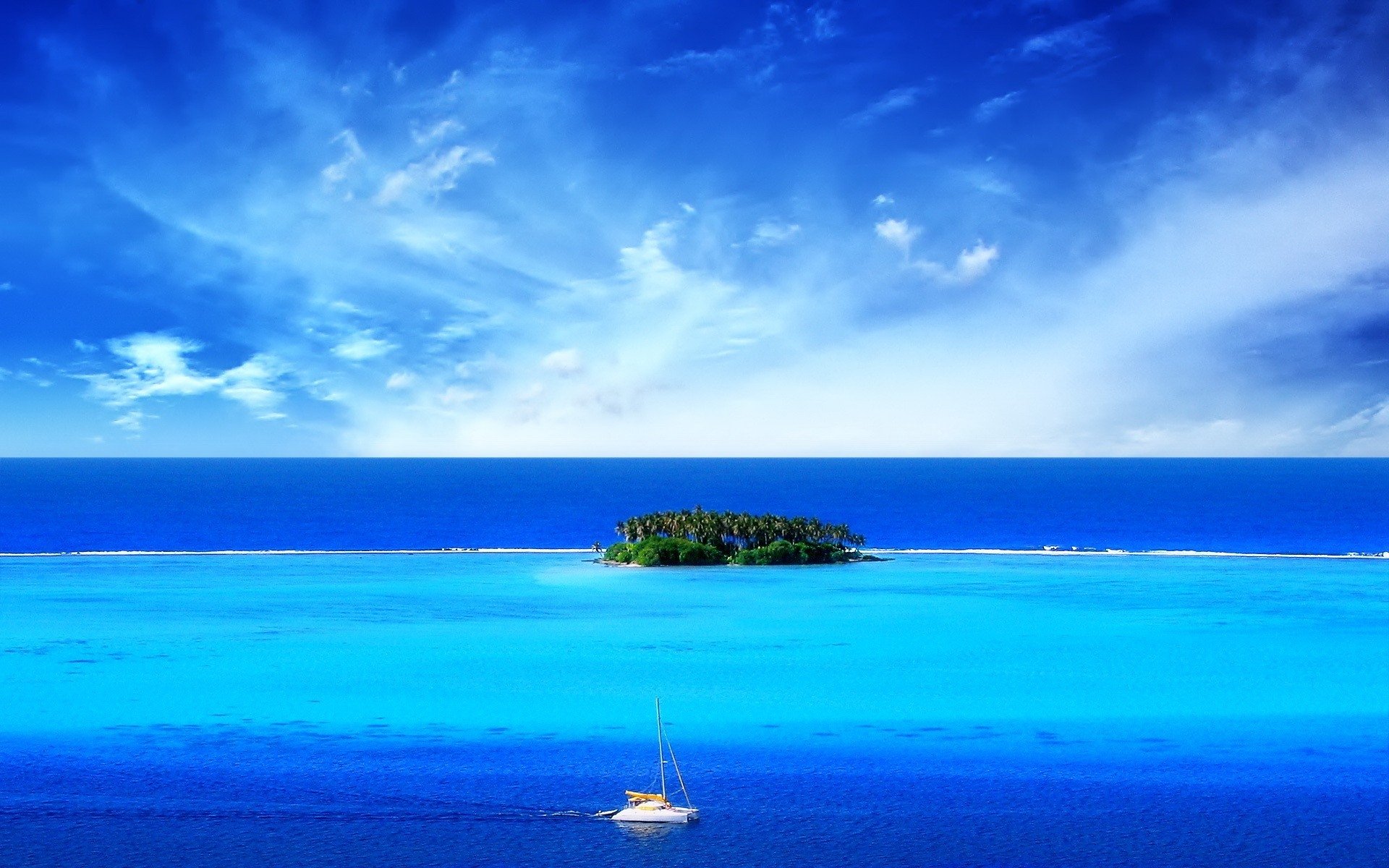 A small island surrounded by clear blue ocean under a vibrant sky, showcasing the beauty of nature and tranquil island life.