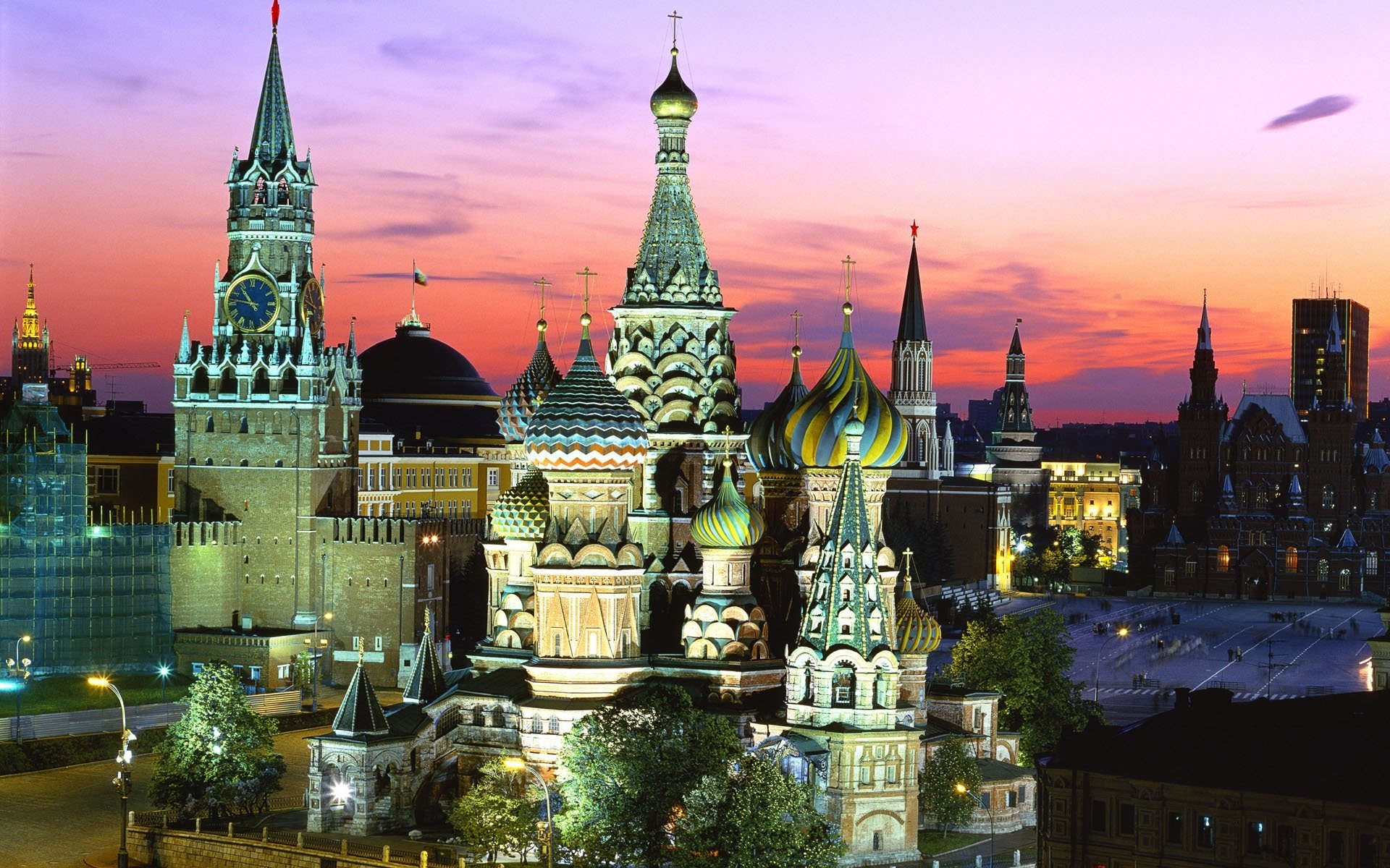 Saint Basil's Cathedral and Kremlin towers at sunset in Moscow, Russia, colorful onion domes of the historic religious cathedral and surrounding buildings.
