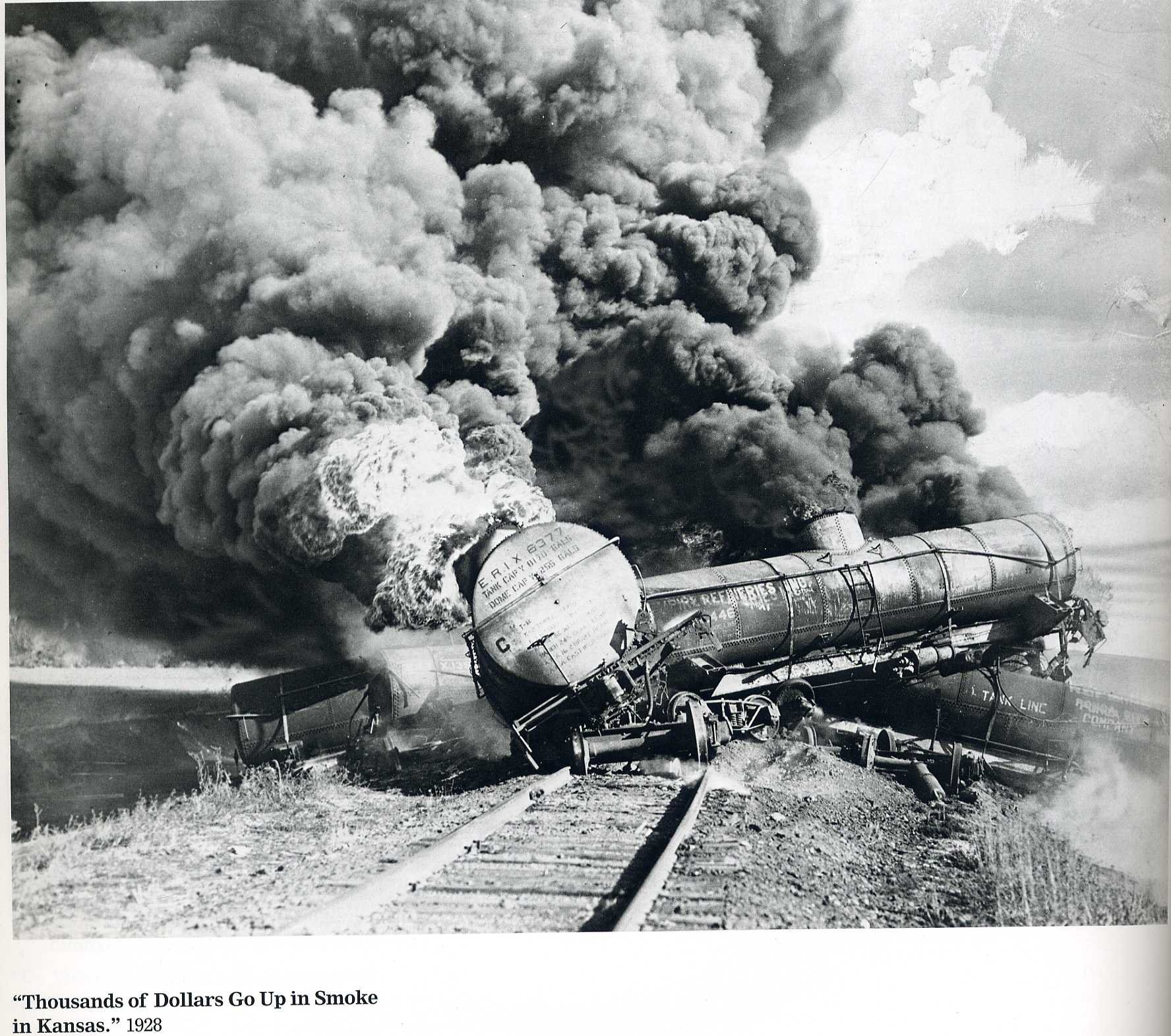 A derailed train, engulfed in smoke and flames, rests on the tracks, depicting the aftermath of a disastrous incident. The scene conveys intense destruction and chaos.