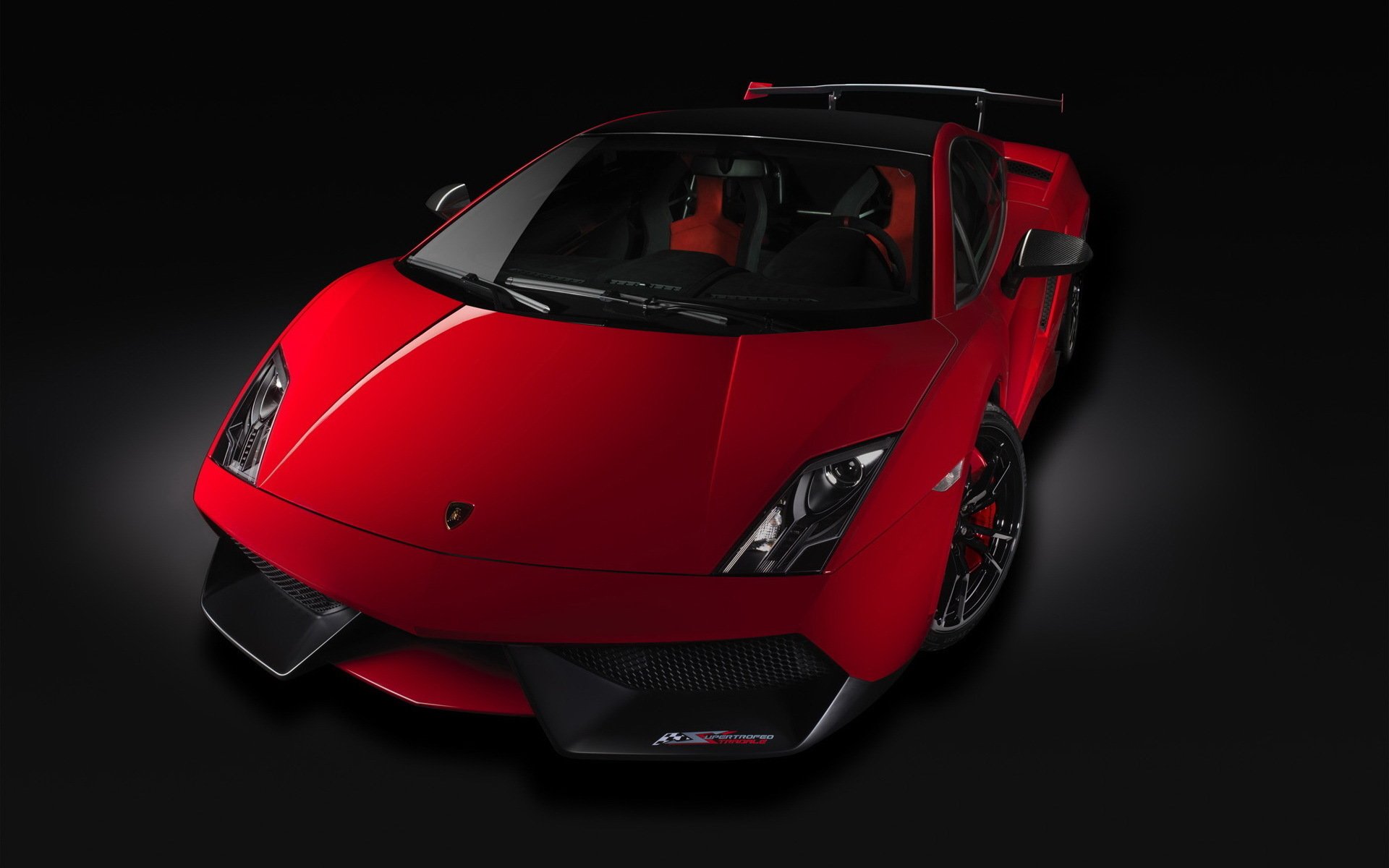 A striking red Lamborghini Gallardo is showcased from an overhead angle, highlighting its sleek design and sporty features against a dark background.