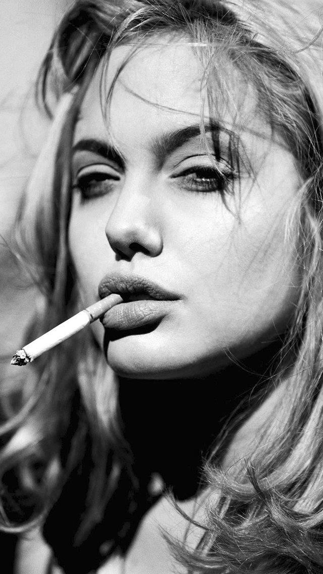 A striking black-and-white portrait of celebrity Angelina Jolie, featuring her with a cigarette, exuding confidence and allure.