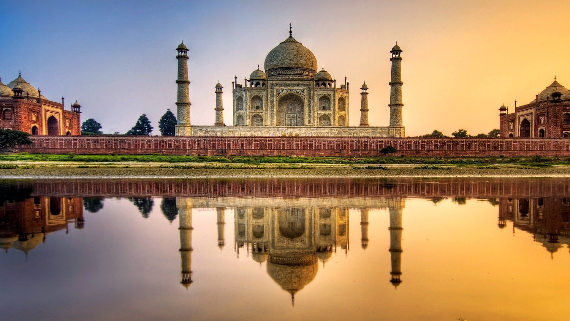 A stunning view of the Taj Mahal, a remarkable man-made structure, reflected in the tranquil water at sunset, highlighting its majestic architecture and serene surroundings.