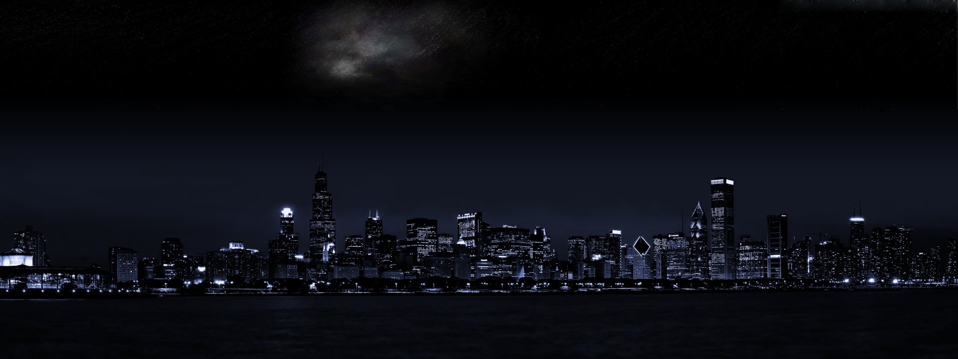 Nighttime city skyline with illuminated buildings reflecting human-made urban architecture against a dark sky.