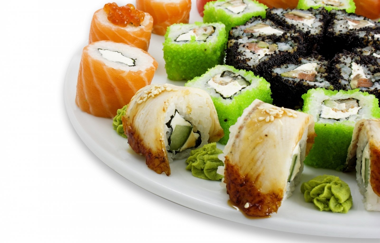 A colorful assortment of sushi rolls featuring salmon, avocado, and various fillings, served on a white plate with wasabi.