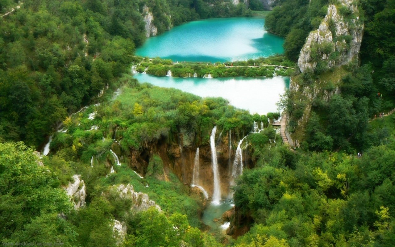 A stunning view of Plitvice Waterfalls cascading into turquoise pools, surrounded by lush green nature.