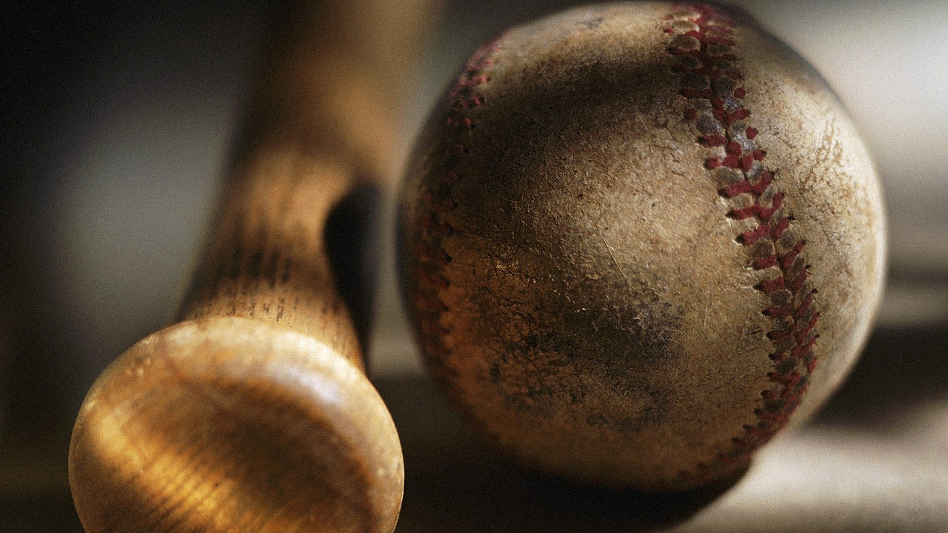 A weathered baseball rests beside a wooden bat, capturing the essence of America's favorite pastime in this evocative sports still life.