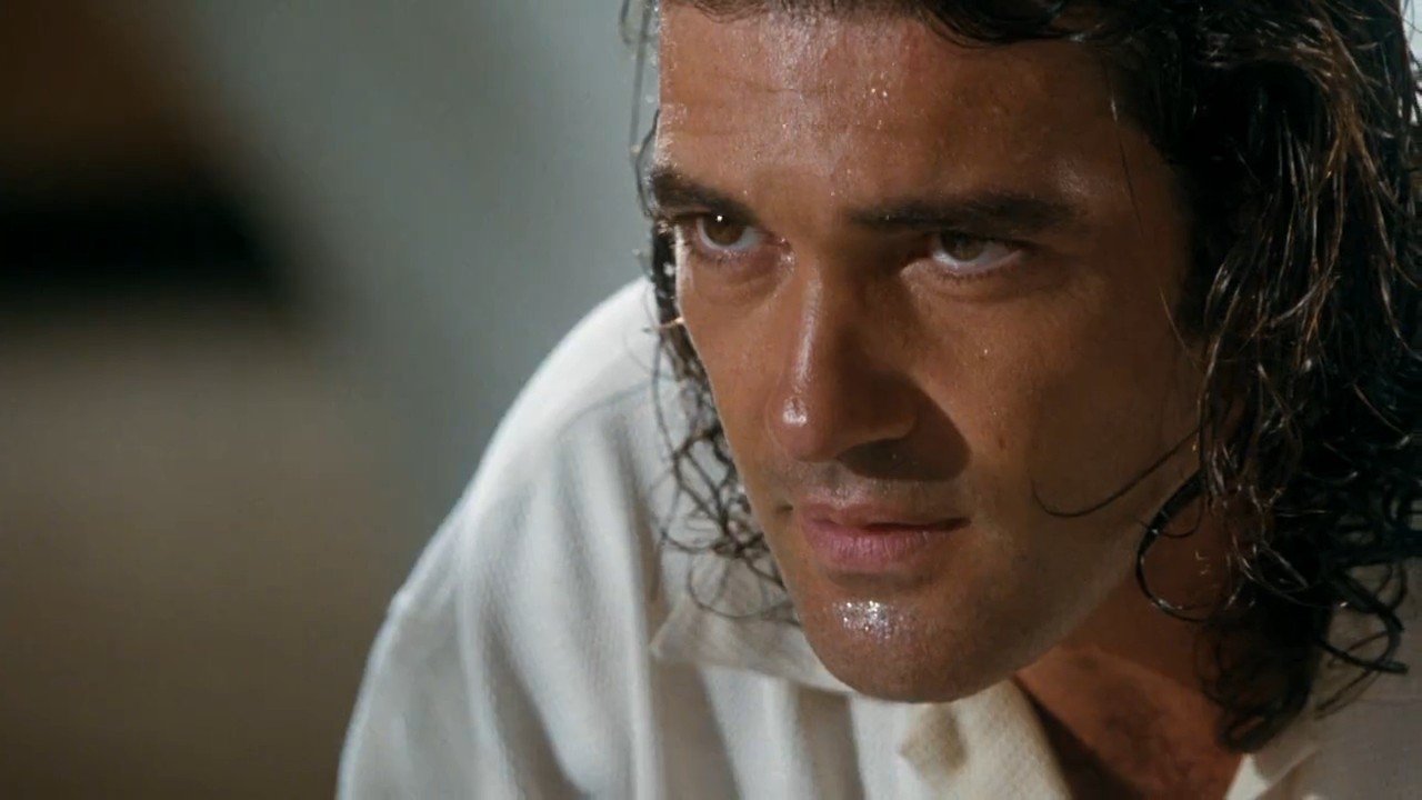 Close-up of an intense, sweaty man with wet dark hair and a white shirt, staring ahead in a tense moment from the 1995 movie Assassin.