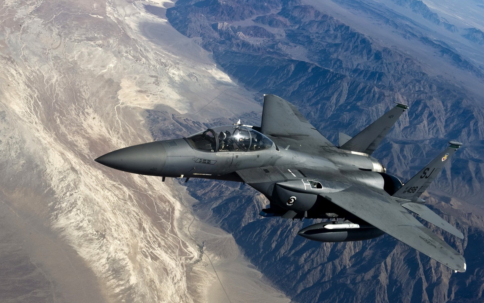 An F-15E Strike Eagle flies over a rugged mountainous landscape, showcasing its sleek design and advanced capabilities in military aerial operations.