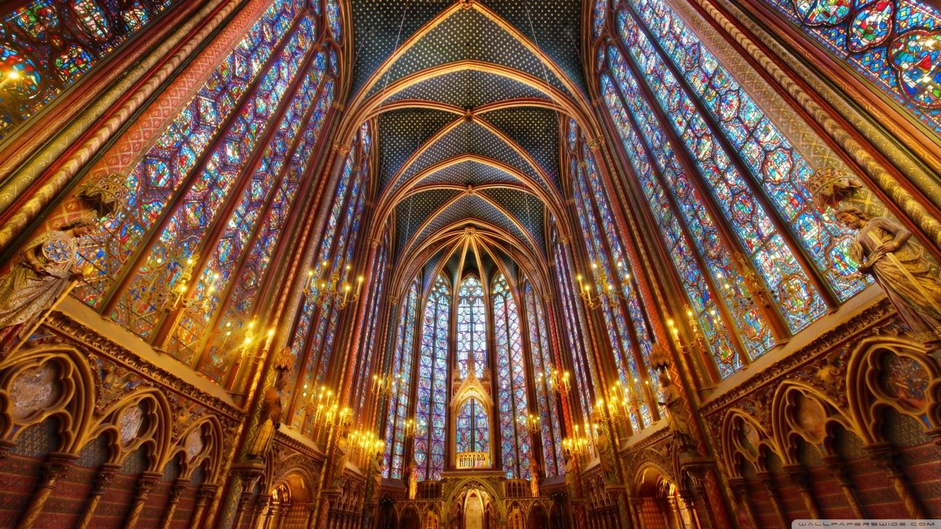 Interior view of Sainte-Chapelle cathedral showcasing its towering stained glass windows and intricate Gothic architectural details.