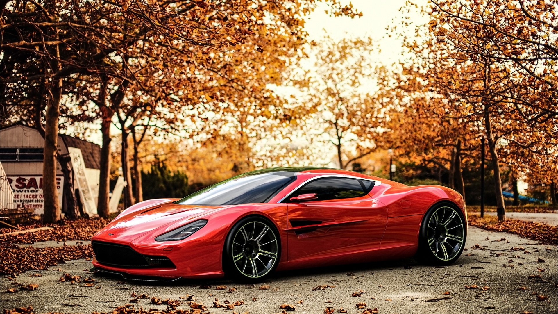 A striking red Aston Martin DBC is parked amidst vibrant autumn foliage, showcasing its sleek design against a backdrop of golden leaves.