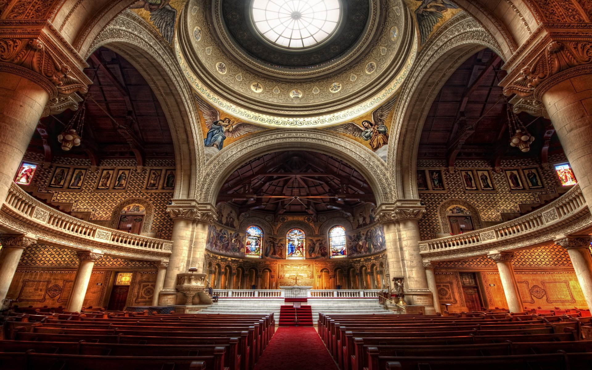 Interior view of Stanford Memorial Church showcasing its ornate dome, detailed arches, and religious artwork under a central skylight.